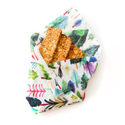 Granola bars wrapped in a reusable beeswax wrap with a colorful modern trees design. 